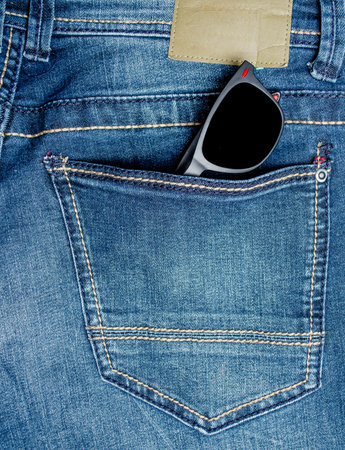 Black sunglasses in the back pocket of blue denim jeans on a casual summer day, close-up for fashion or lifestyle conceptの写真素材