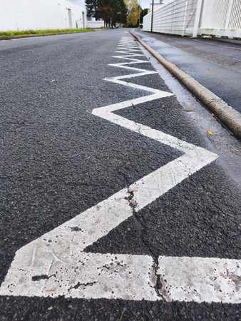This image shows a white zigzag road marking on a dark asphalt surface, indicating a no-stopping zoneの写真素材