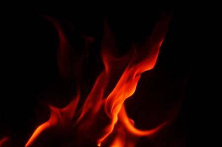 The fiery orange and red hues of the flames contrast beautifully with the deep black backdrop, making a striking imageの写真素材