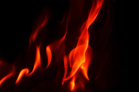 The fiery orange and red hues of the flames contrast beautifully with the deep black backdrop, making a striking imageの写真素材