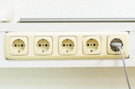 A close-up shot shows a row of electrical outlets, with one outlet actively in use