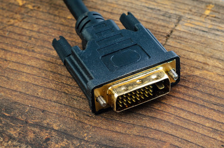 This image shows a DVI connector, a common interface for video displays, resting on a rustic wooden...