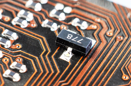 Macro close up of a dusty SMD transistor on a motherboard. Highlights electronics components covered with dust, showing hardware detail, maintenance needs, and PC cleaning concepts.の写真素材