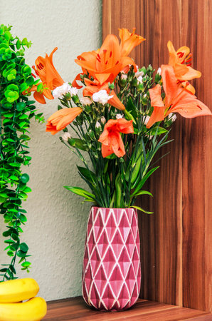 Vibrant orange lilies in a decorative vase, a beautiful floral arrangement for home decorの写真素材