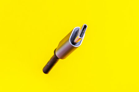 This close-up shot of a USB-C cable against a vibrant yellow backdrop is ideal for tech-related projectsの写真素材
