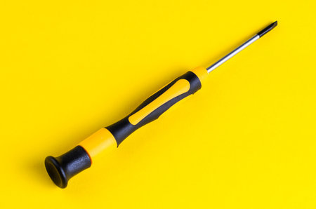 Close-up of a yellow and black screwdriver on a bright yellow backgroundの写真素材