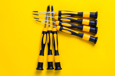 Screwdrivers arranged on a bright yellow background, top-down view