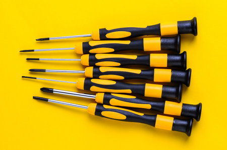 Set of screwdrivers with yellow and black handles on a bright yellow backgroundの写真素材