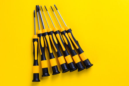 Set of screwdrivers with yellow and black handles on a bright yellow backgroundの写真素材