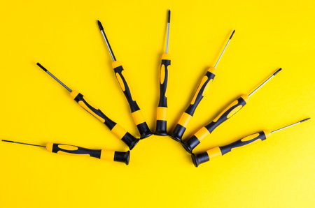 Screwdrivers arranged in a semi-circle on a bright yellow backgroundの写真素材