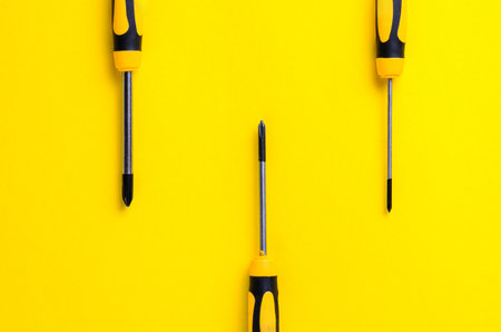 Screwdrivers arranged on a vibrant yellow background for a minimalist designの写真素材