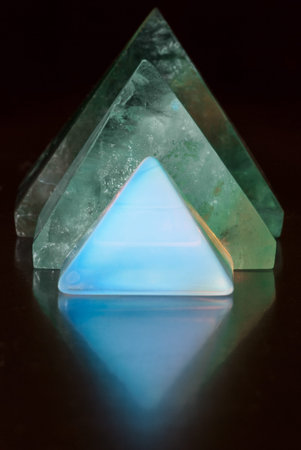 Three beautiful gemstone pyramids reflecting on the ground.の写真素材