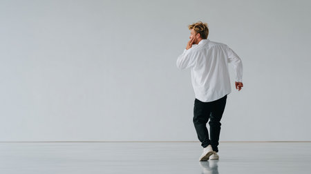 full length view of stylish young man in white shirt dancing on greyの素材