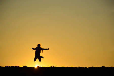 teenager girl posing in a field on a background of golden sunsetの写真素材