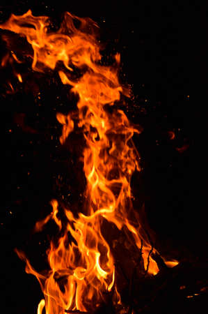 in the photo of a dark night, a yellow-red flame burns, firewood is visible from belowの写真素材