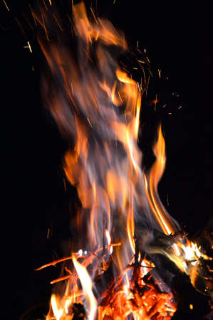 in the photo of a dark night, a yellow-red flame burns, firewood is visible from belowの写真素材