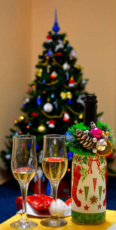 champagne, two glasses of wine, a Christmas tree decorated in the backgroundの写真素材