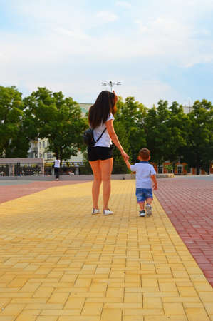 girl walks around the city with a boy. mom walks with her sonの写真素材
