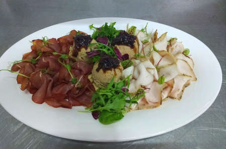 assorted meat from prosciutto, lard and balls of rabbit paste on a white plate.の写真素材
