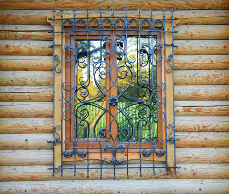in a wooden house on the window there is a beautiful, wrought-iron lattice. for safetyの写真素材