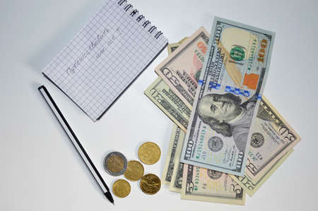 dollars, euro cents, notebook and pen. counting money for travel. in a notebook an inscription in Russian with the question to travel or notの写真素材