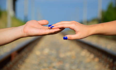 man's hand holds a woman's hand against the background of the sky and the railwayの写真素材