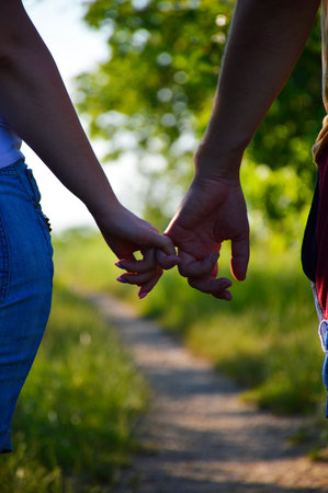 a man and a woman joined hands and walk along the path towards the sunset