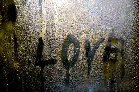 the word love is written on the misted glass, drops of water flow down the glassの写真素材