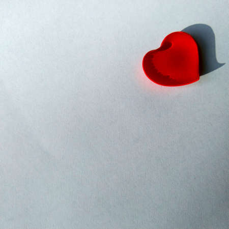 a small red heart filled with water and lies on a white textured backgroundの写真素材