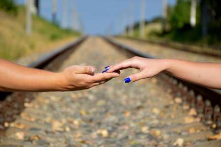 male hand holds female hand, in the background a blurred view of the railwayの写真素材