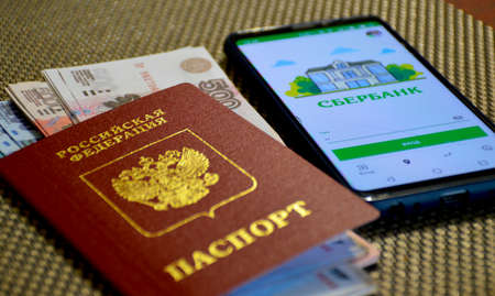 passport of a citizen of Russia with money invested inside, next to there is a switched on smartphoneの写真素材