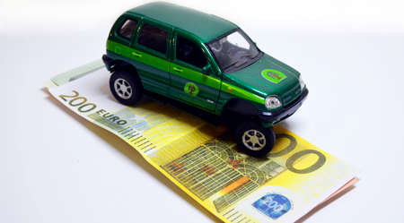 a toy car with a polished front wheel stands on a wad of paper moneyの写真素材