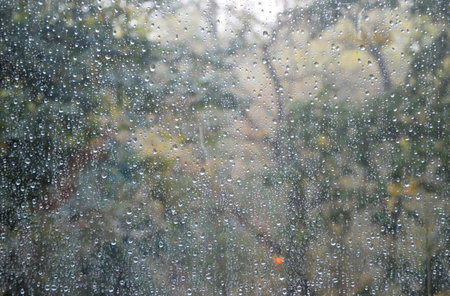 window glass with many drops of water after the last rain, cloudy weather outside the windowの写真素材
