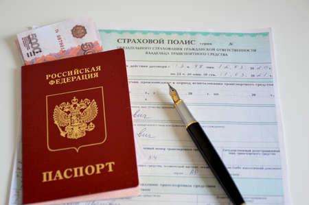 passport of a citizen of Russia with money invested inside and a completed insurance policy for the carの写真素材