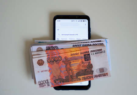 a bundle of Russian money on a smartphone, on the screen the inscription in Russian "car loans in the Russian Federation"の写真素材
