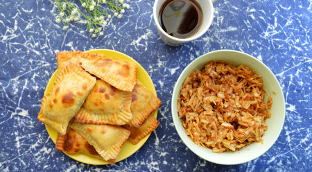 on a blue background a mug of tea, homemade cakes and grated apple filling for piesの写真素材