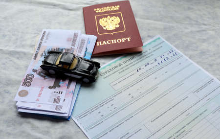 a blank form of auto insurance, a passport and a pack of Russian rubles, a black model of a retro car stands on the moneyの写真素材
