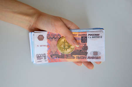 gold coin bitcoin and Russian rubles in a man's hand on a white backgroundの写真素材