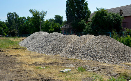 a long pile of construction gravel is lying on the ground. the stone is prepared for laying the drainage of the future stadiumの写真素材