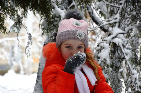 young girl posing among the branches of a tree with snow flakes, the girl dreamily looks at the...