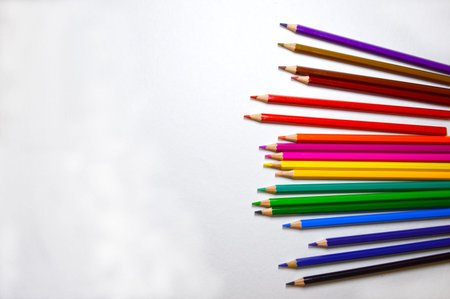 wooden multicolored pencils are lined with a fan in a chaotic order on a white background. art and...