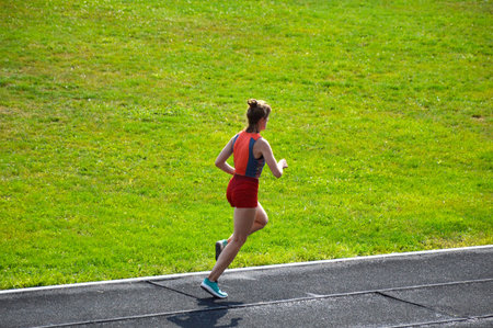 A young girl runs on a treadmill at the city stadium on a sunny morning. fitness and healthy lifestyle. Sports and recreationの写真素材