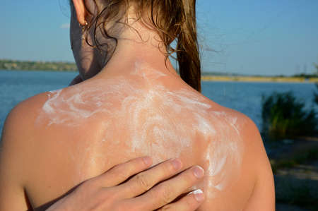 hands are rubbing suntan cream on the back. Close-up of applying sunscreen. Summer skin and body care. Man using foam to protect the skin. sun protection conceptの写真素材