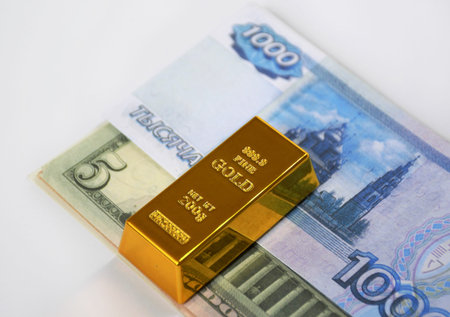 banknotes of dollars and Russian rubles, laid out in small bundles on top of a gold ingot. the...