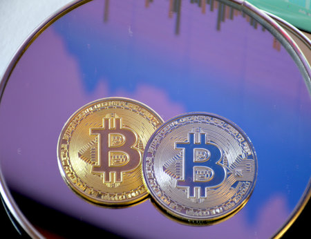 two bitcoin coins on a mirror glass in dim light. concept of transition to digital currency and...