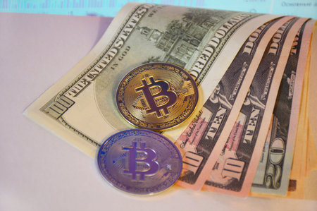 two coins bitcoin and us dollars on a light background in dim light. concept of transition to...