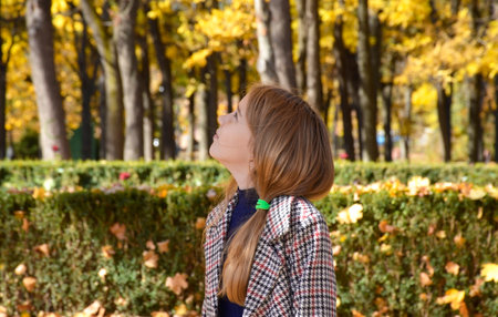 Beautiful fashionable girl with long blond hair in a stylish coat posing in the autumn park. outdoor portrait. Women's autumn fashion conceptの写真素材