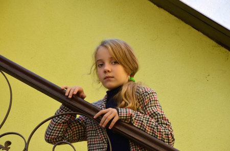 a beautiful girl in a plaid coat put her hands on the iron railing of the stairs and thought. walks...