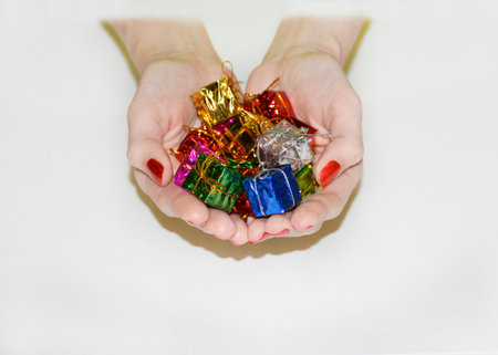 small multi-colored boxes with gifts in female hands on a white background. the concept of congratulations on holidays, anniversaries and celebrationsの写真素材