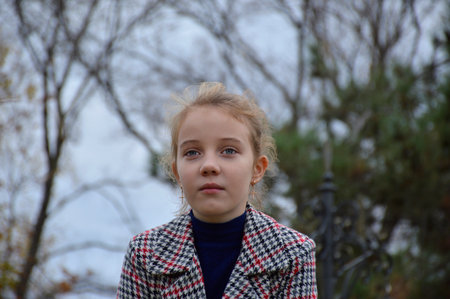 portrait of a beautiful girl in a plaid coat on the background of nature close-up. the child smiles a little and looks away. active lifestyle and outdoor activitiesの写真素材